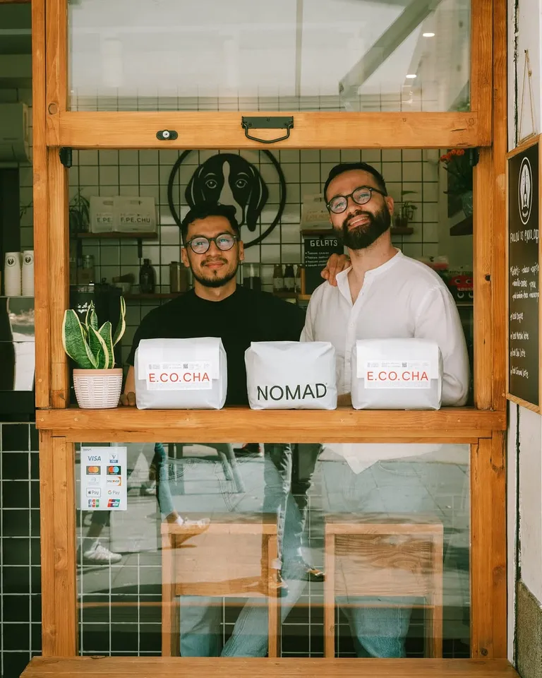 Dos baristas en la ventana con bolsas de café Nomad