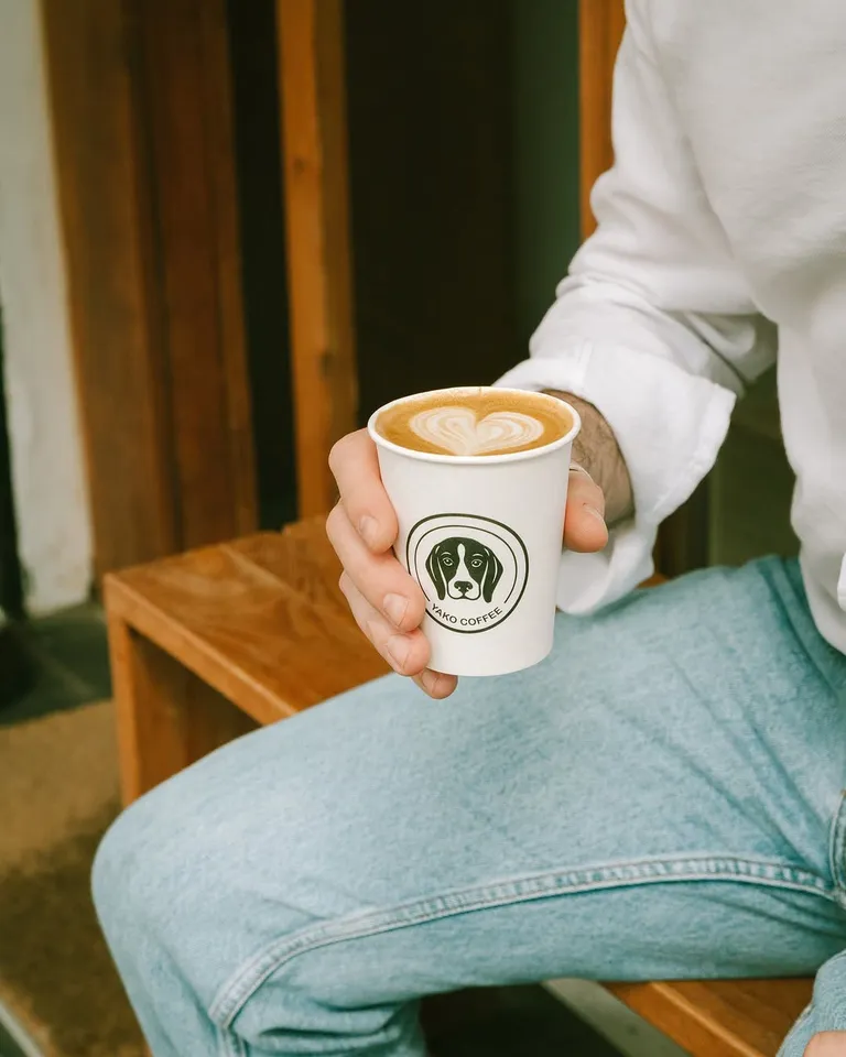 Un café con leche en vaso de Yako Coffee, con la cara del beagle